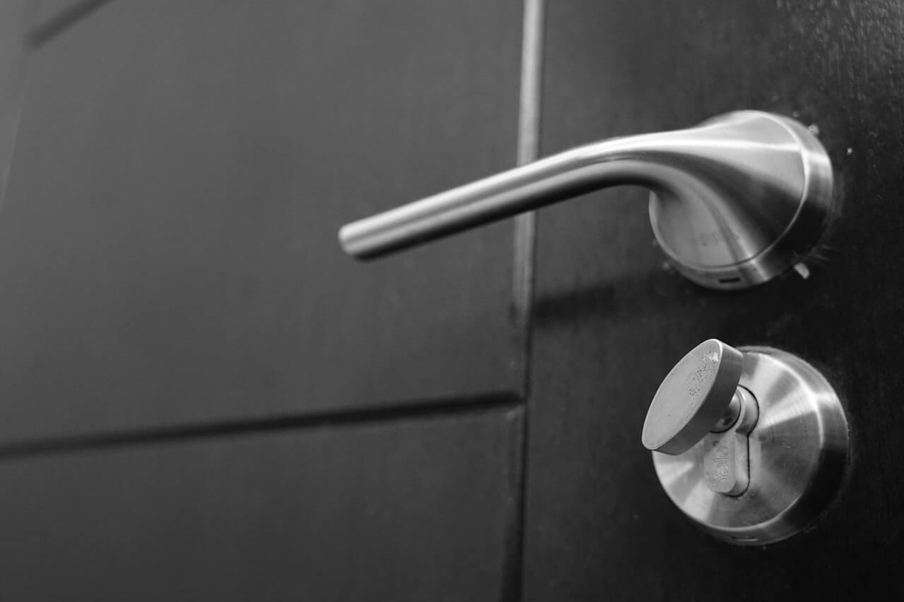 a closeup photo of silver door handle and deadbolt lock on black door